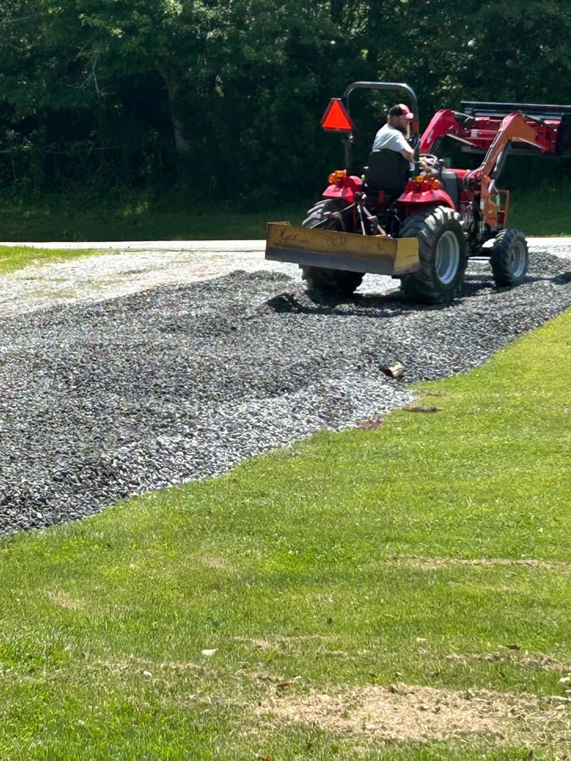 Tractor spreading gravel on a grassy area, enhancing outdoor landscaping project.